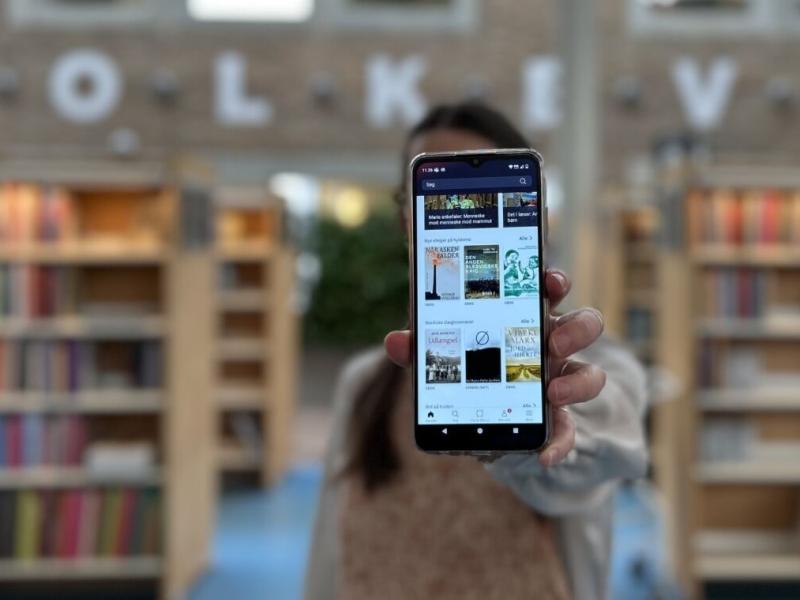 Line holder sin telefon frem til kameraet, telefonen viser app'en Biblioteket