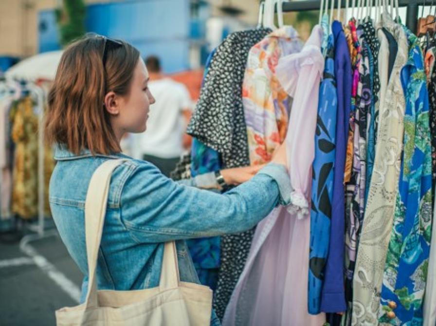 En person står ved en bøjlestang og kigger på forskelligt tøj.
