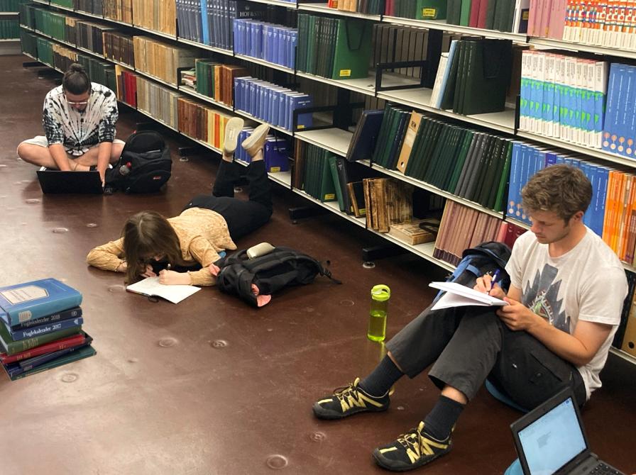 Tre tidligere medlemmer af skriveskolen laver skriveøvelse i Hovedbibliotekets magasin